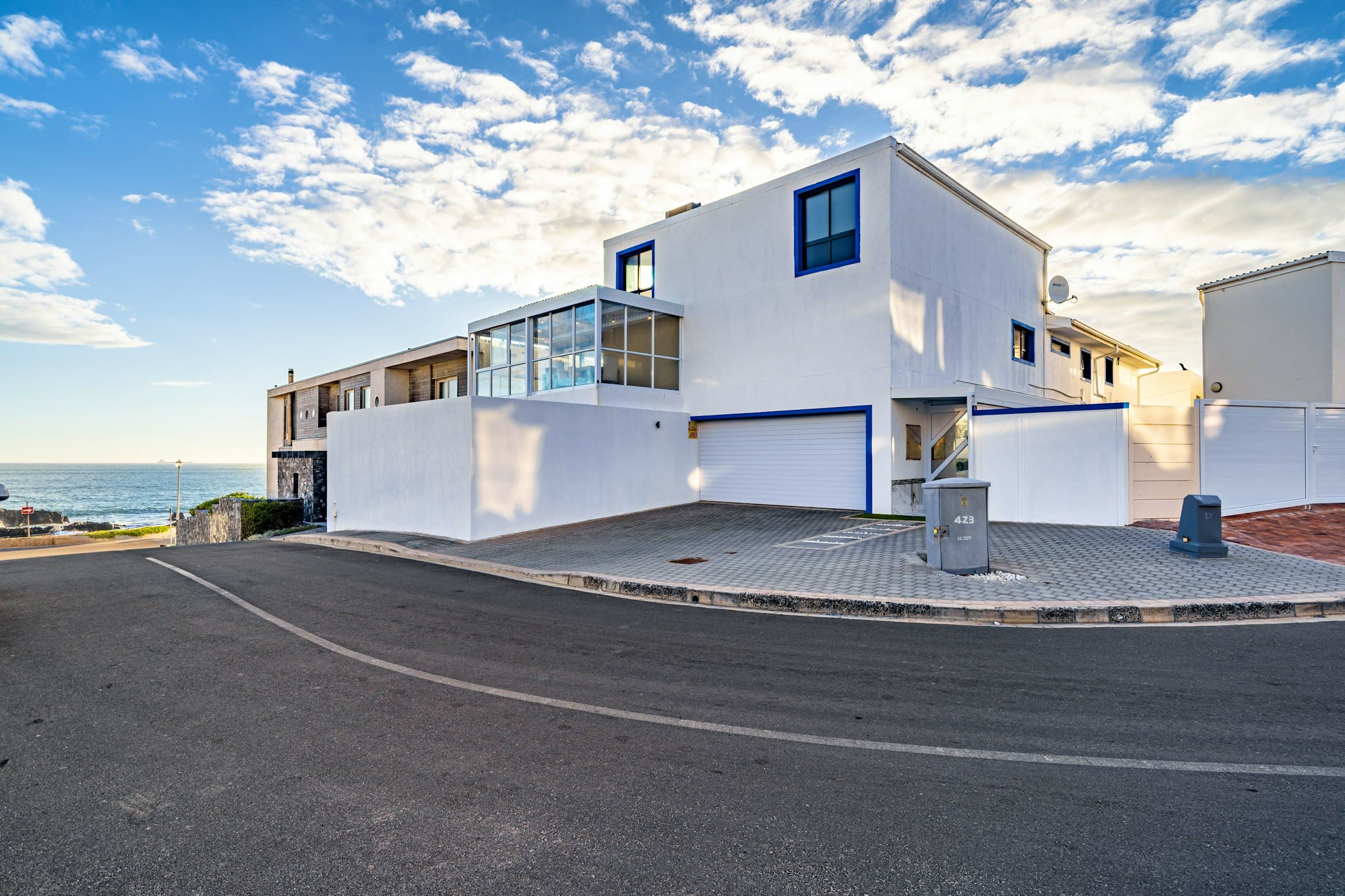 White exterior of The Lighthouse with cobalt window frames, viewed from the road
