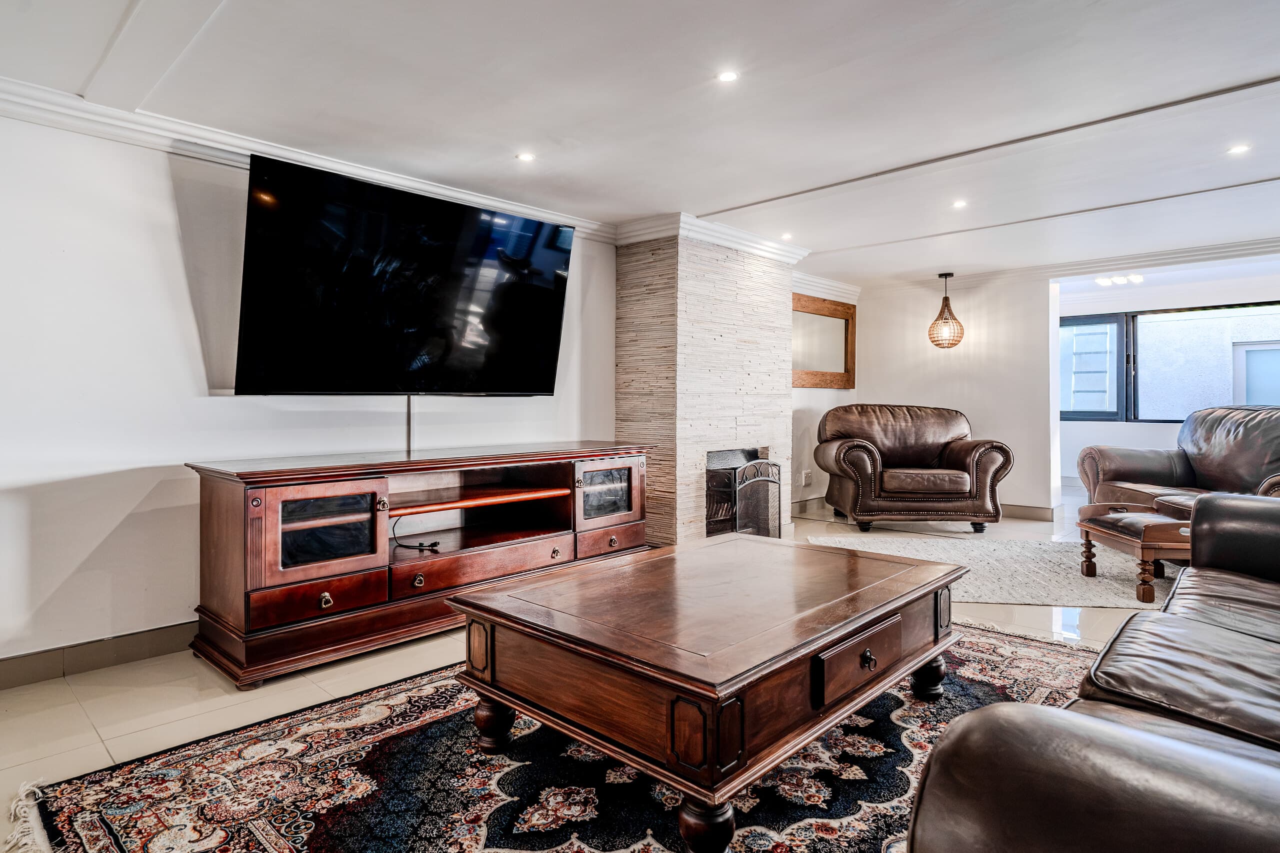 Lounge with leather armchairs, rugs and a television