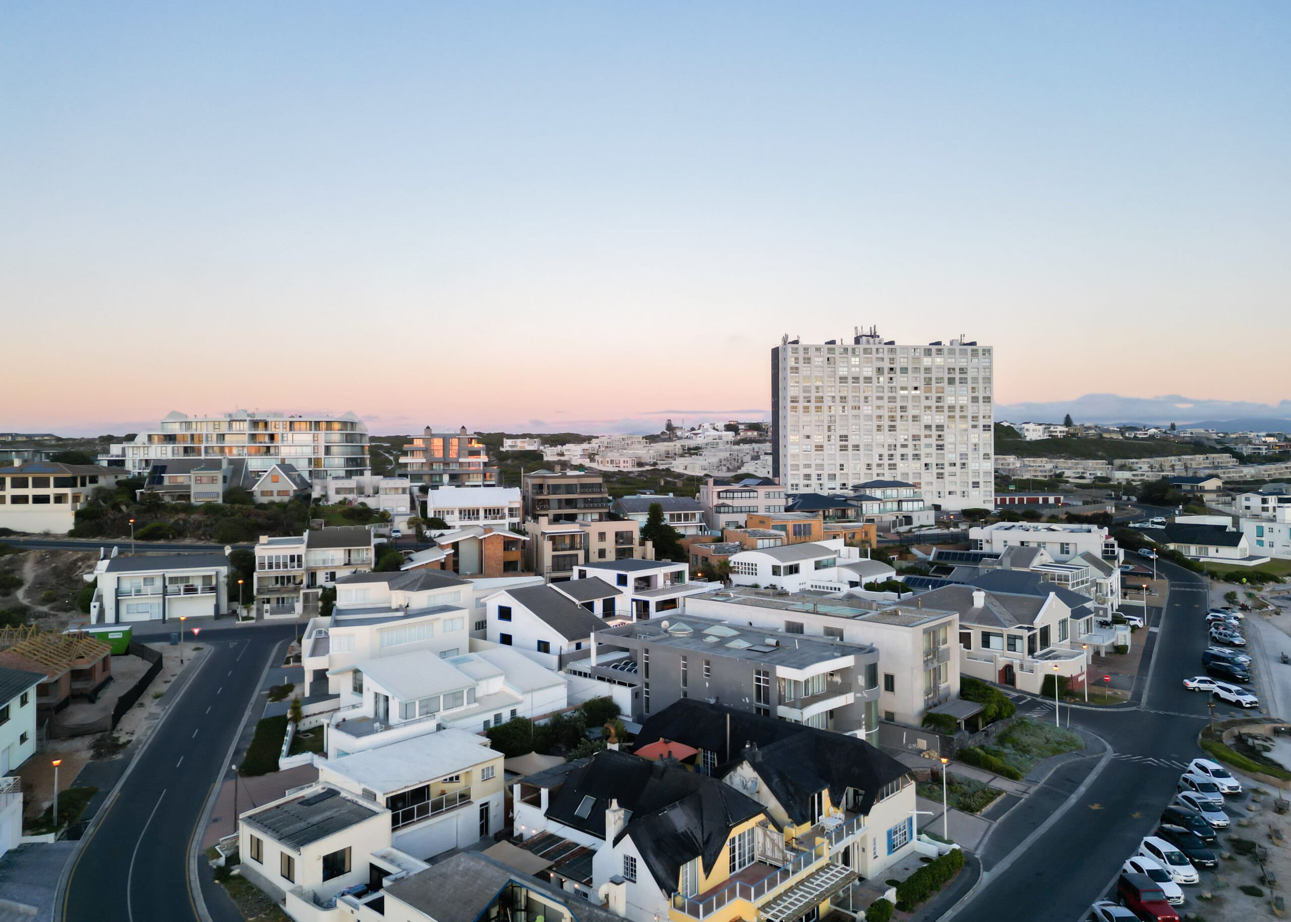 An aerial view over the Bloubergstrand shoreline, houses and dune scrub meeting the Atlantic