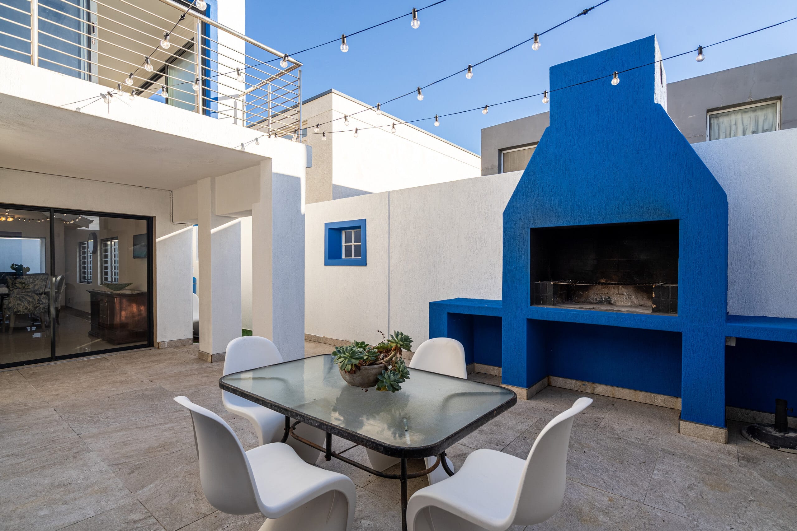 A cobalt-blue built-in braai and fireplace on a sheltered terrace at The Lighthouse, strung with festoon lights