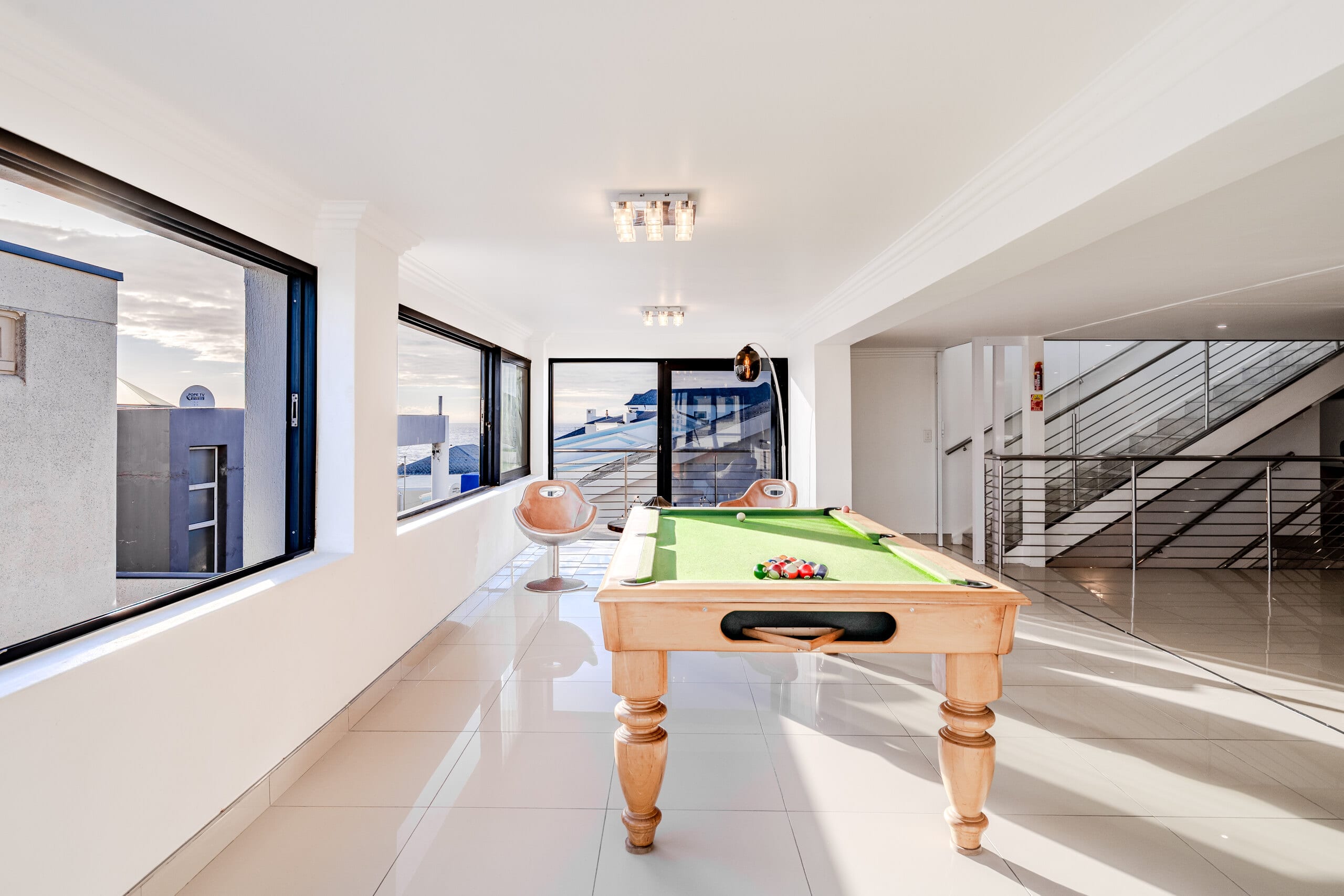 The pool-table room at The Lighthouse, a full-size table beside a long run of windows looking out to sea